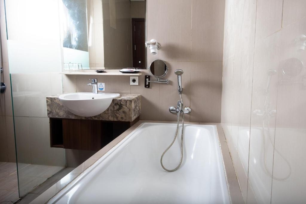 un bagno con vasca, lavandino e doccia di Pakons Prime Hotel a Tangerang