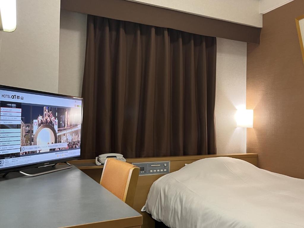 a hotel room with a bed and a flat screen tv at Hotel Alpha-One Koriyama in Koriyama