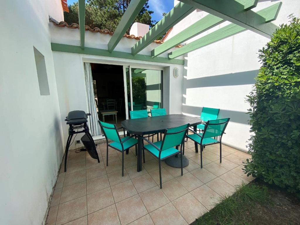 d'une terrasse avec une table noire et des chaises bleues. dans l'établissement Maison proche forêt, 2 chambres, terrasse et parking - 6 personnes, St Jean de Monts - FR-1-323-523, à Saint-Jean-de-Monts