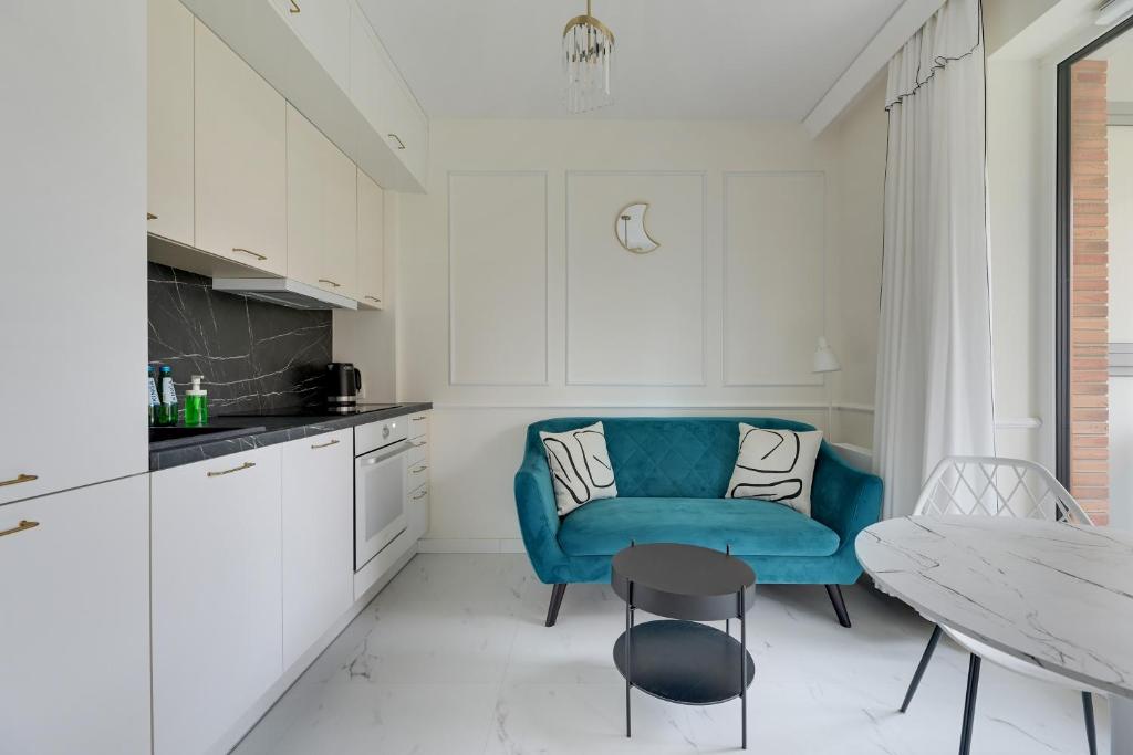 una cocina con una silla azul y una mesa en Sunny Garden by Grand Apartments en Gdansk