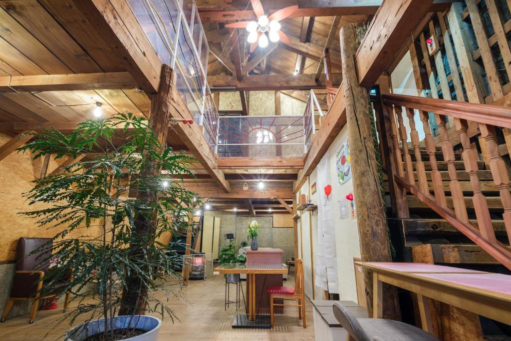 a room with wooden ceilings and a table and a plant at Stone Lodge 小樽 in Kita-hamachō