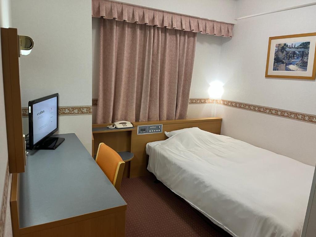 Habitación de hotel con cama y escritorio con ordenador en Hotel Alpha-One Niigata, en Niigata