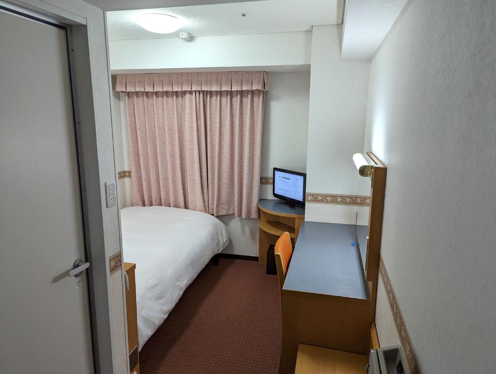 横浜市にあるホテルアルファーワン横浜関内のベッド、デスク、コンピュータが備わるホテルルームです。