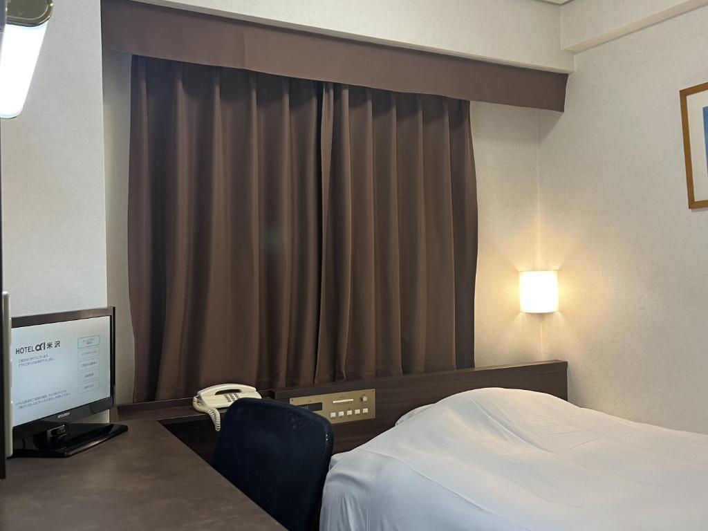 ein Hotelzimmer mit einem Bett und einem Computermonitor in der Unterkunft Hotel Alpha-One Yonezawa in Yonezawa