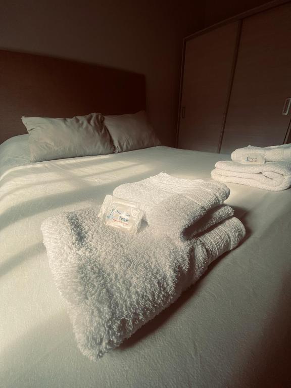 a bed with white blankets and towels on it at Sur alojamiento in Ushuaia