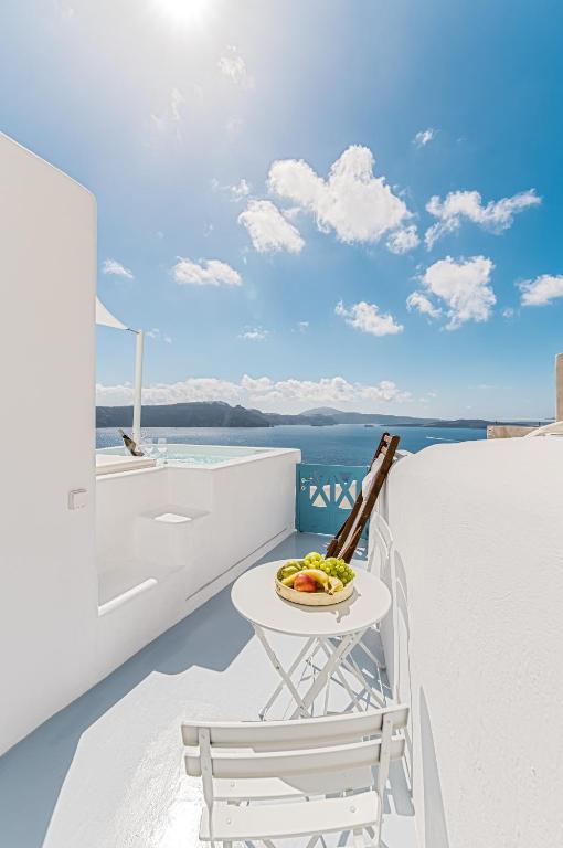 a white balcony with a table and a bowl of fruit at Aristos Life Luxury Cave Villas in Oia