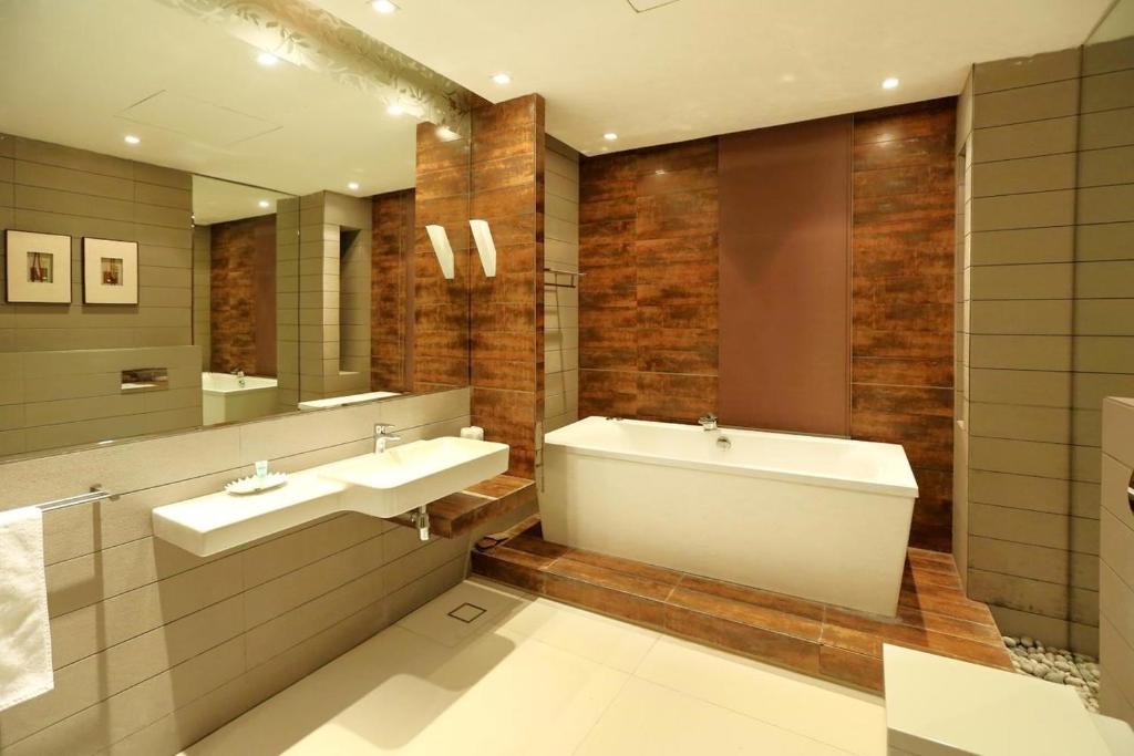 ein Badezimmer mit zwei Waschbecken, einer Badewanne und einem Spiegel in der Unterkunft Sway Suites in Manama