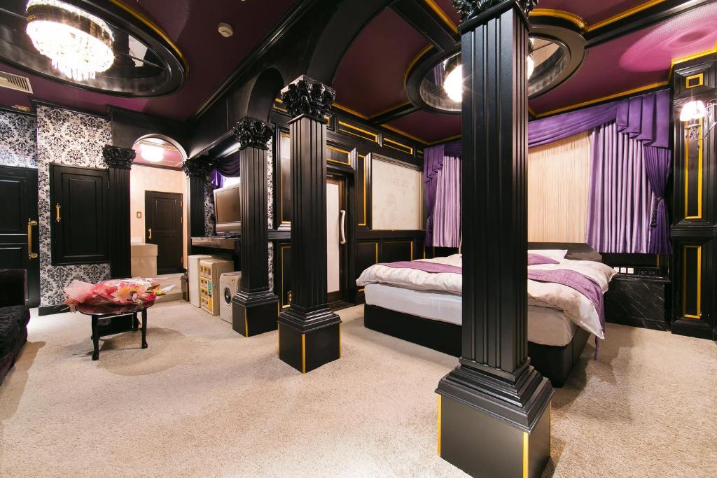 een slaapkamer met een bed, zuilen en paarse muren bij ラブホテル tabasaサンレモ in Fukuoka