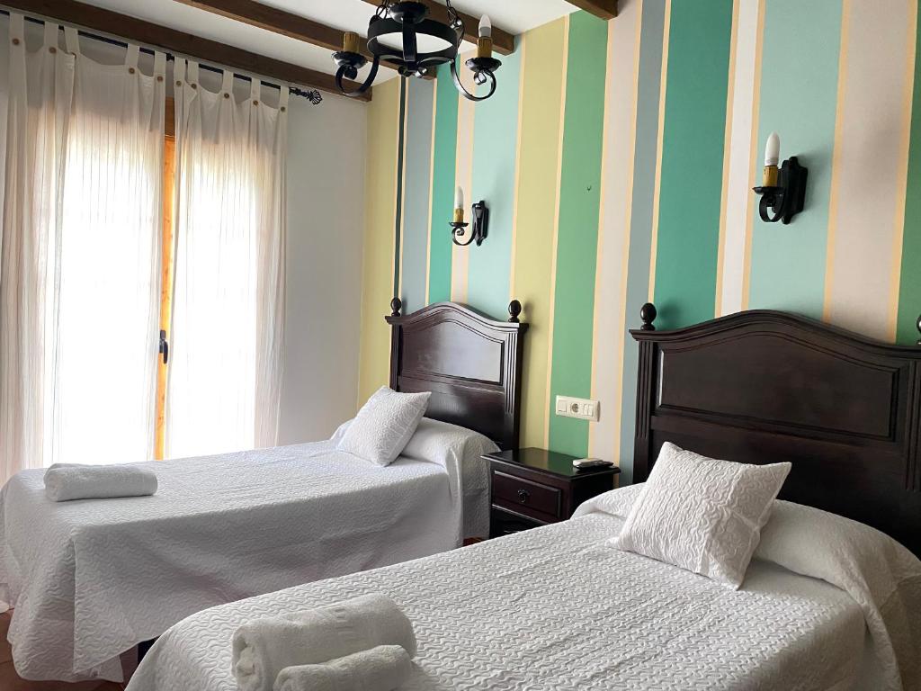 2 Betten in einem Zimmer mit grünen und weißen Streifen in der Unterkunft Hostal El Descanso Del Emperador in Jarandilla de la Vera
