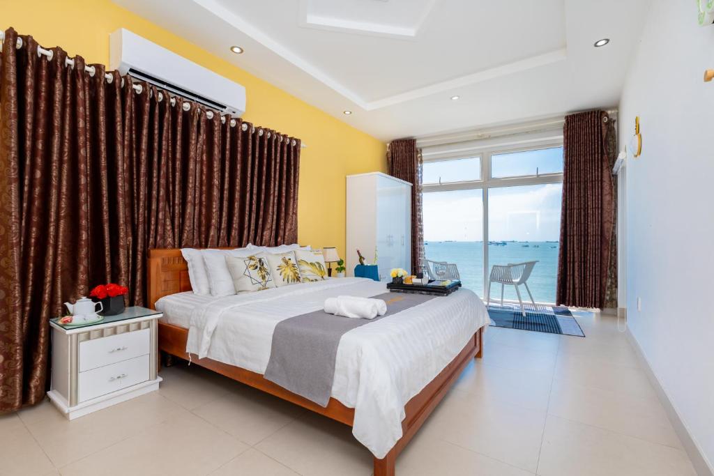 een slaapkamer met een groot bed en een groot raam bij Villa Giáp biển 69 Trần Phú, Bãi trước in Vung Tau