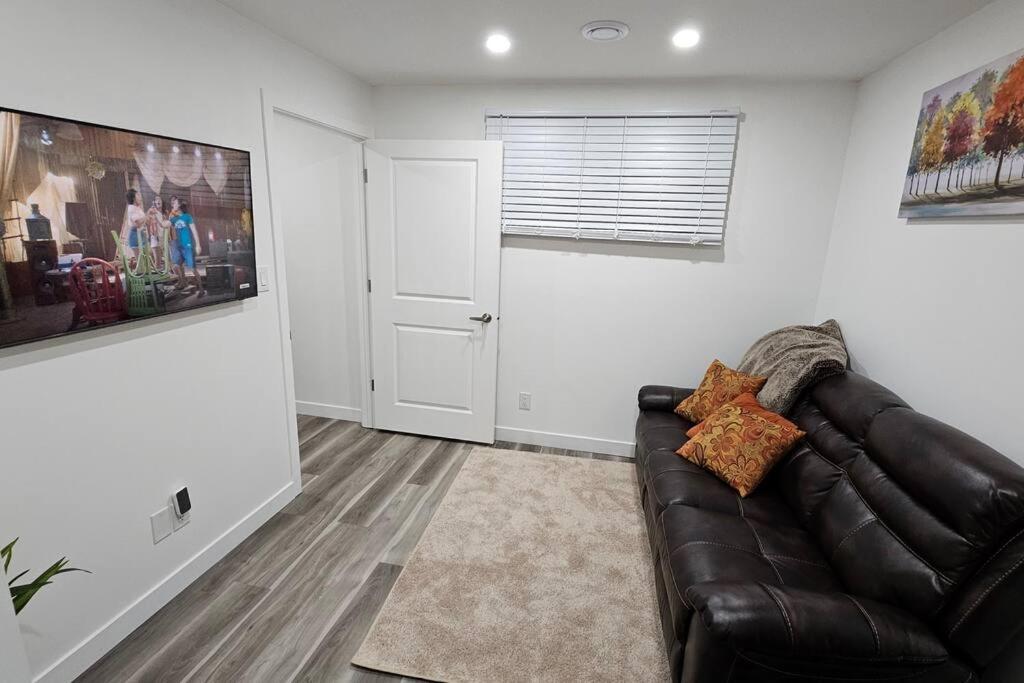 a living room with a leather couch and a window at New Decently Furnished Suit in Regina