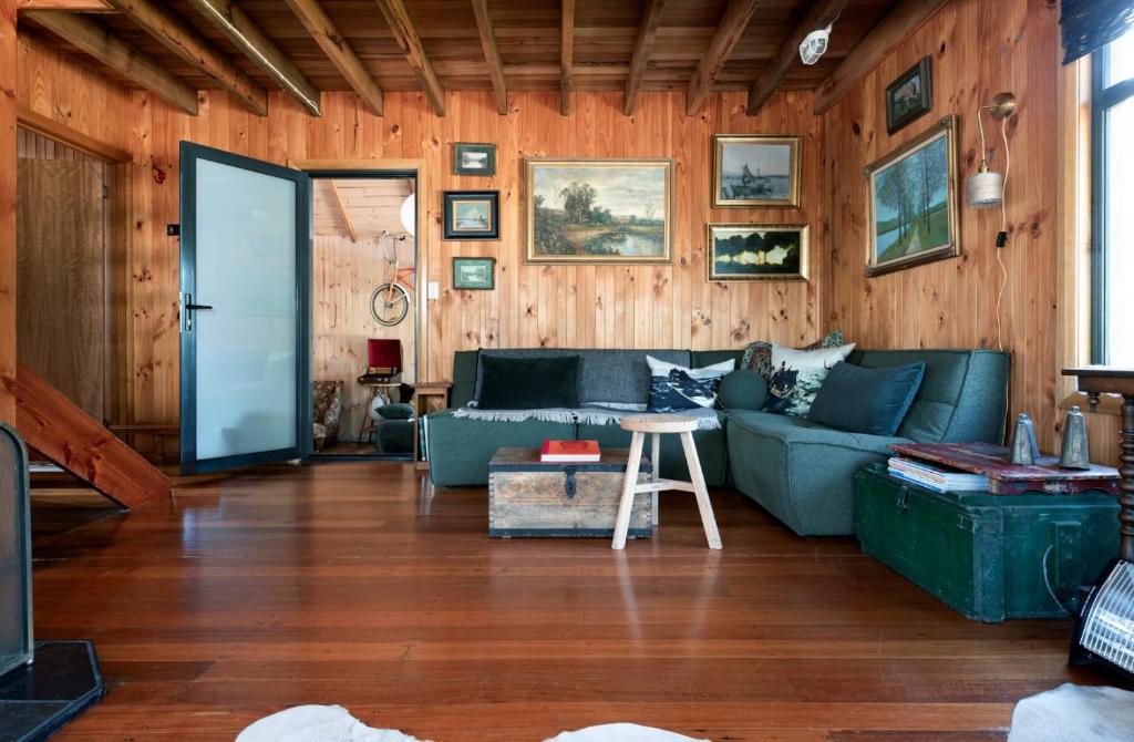 a living room with a blue couch and wooden walls at Rustic Barn by the Bay in Low Head