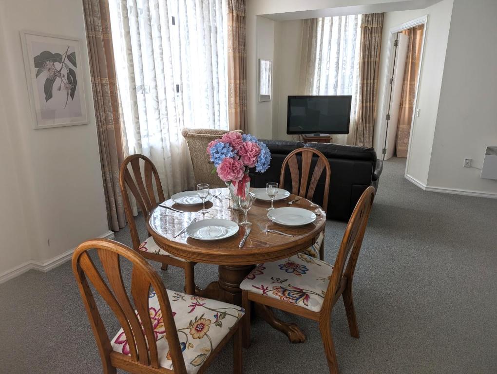a dining room with a table and chairs with flowers on it at Wellington CBD Apartment in Wellington
