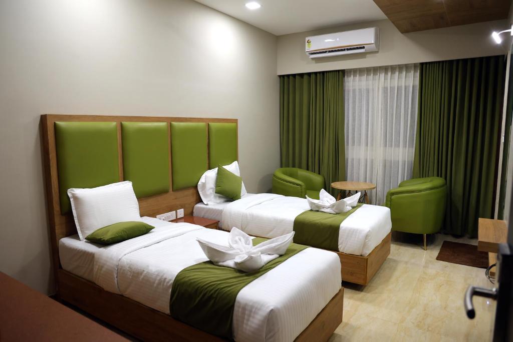 - 2 lits dans une chambre d'hôtel avec des touches de vert dans l'établissement Miot Grande, à Chennai