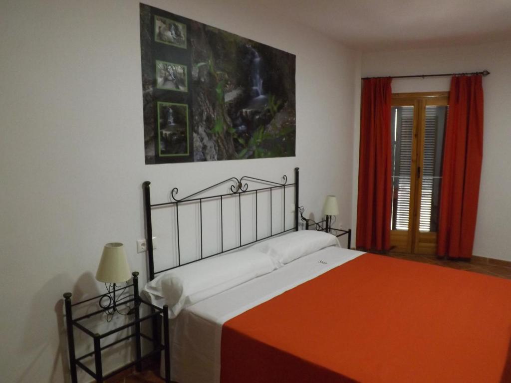 a bedroom with a bed with an orange blanket at Casa Rural ENTRESIERRAS in Beires