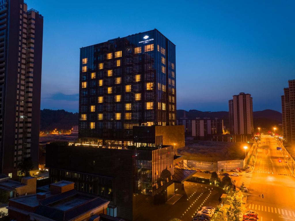 a tall building in a city at night at Maison Albar Hotels Leshan in Leshan