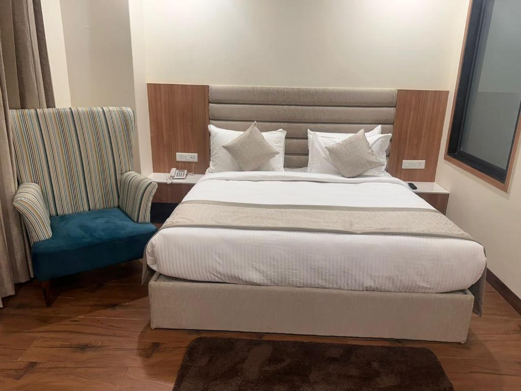 Cilantro Comfort Jaipur في جايبور: غرفة نوم بسرير كبير وكرسي ازرق