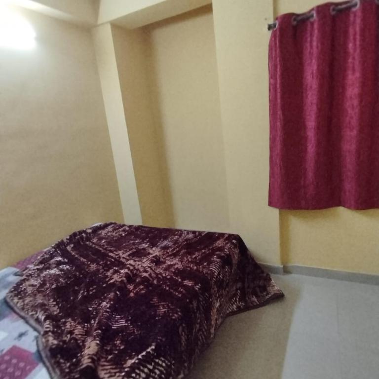 a bedroom with a purple blanket on the floor next to a window at Piyari Home stay 2 in Kolkata