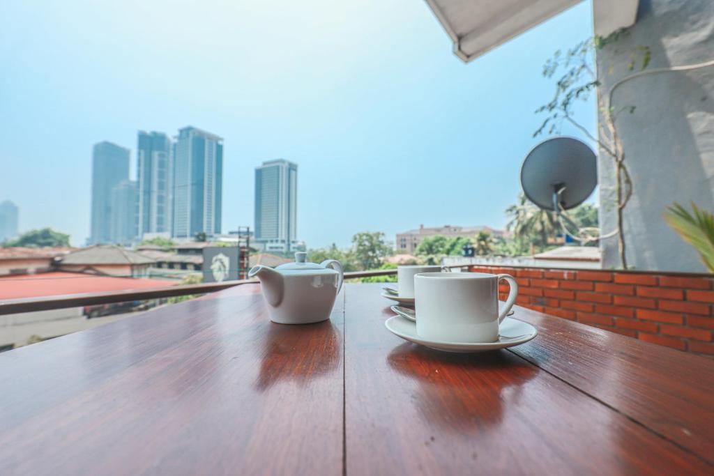 Regent Residencies - Colombo في كولومبو: كوبين قهوة جالسين على طاولة خشبية على شرفة
