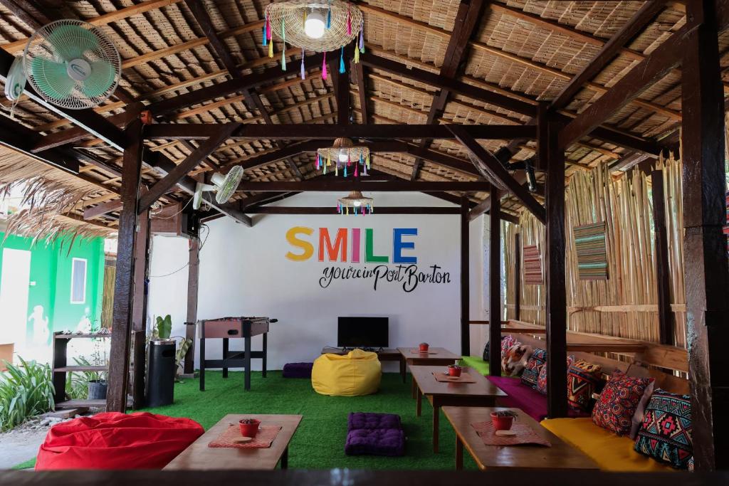 a large room with tables and a smile sign on the wall at Garpeza Backpackers in Port Barton
