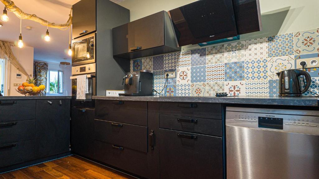 a kitchen with black cabinets and a stainless steel dishwasher at Villa Osao Panahy in Le Patelin
