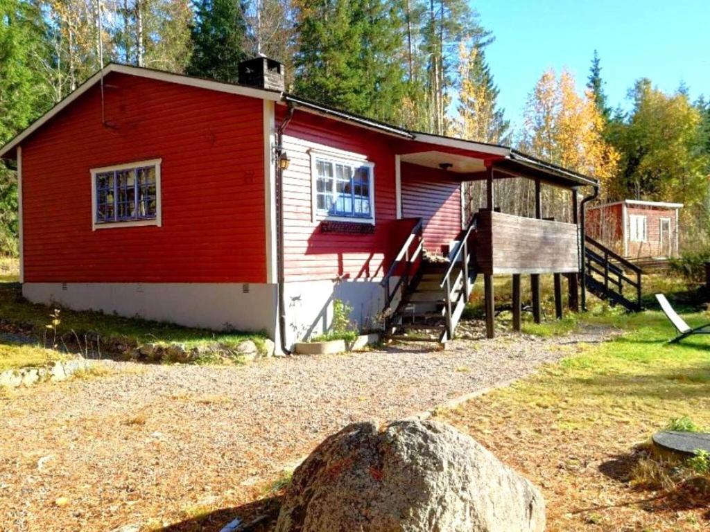 una casa roja con una gran roca delante de ella en Holiday home JÄDRAÅS, en Jädraås