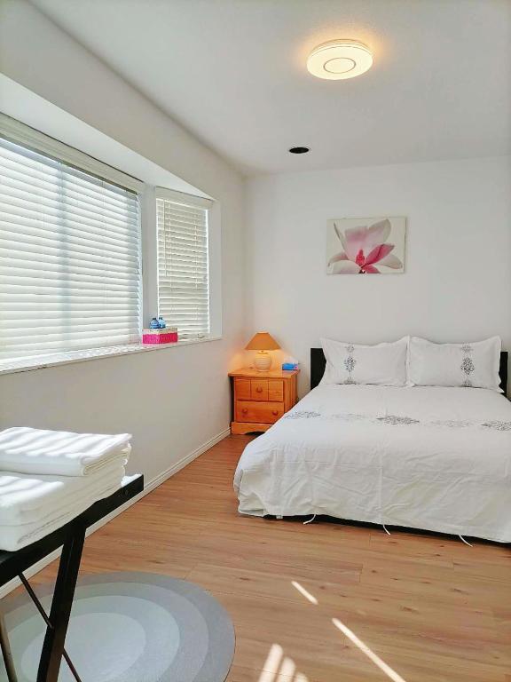 een slaapkamer met een wit bed en een raam bij LLT HomeAway in Vancouver