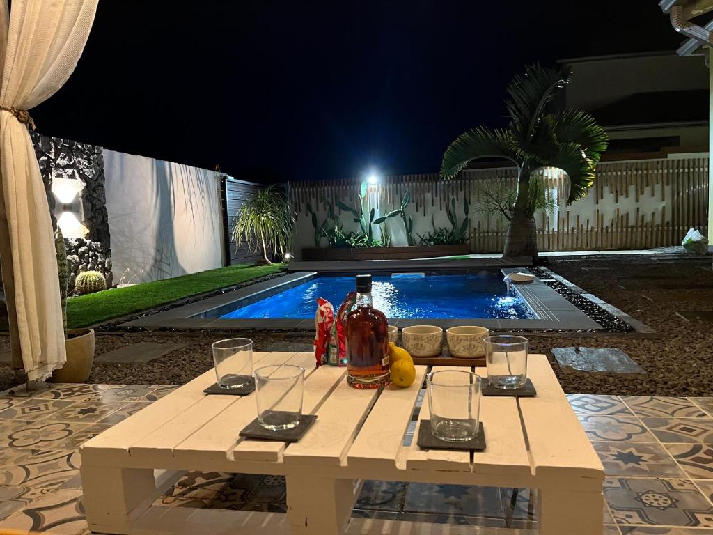 a picnic table in front of a swimming pool at night at Villa Osao Panahy in Le Patelin