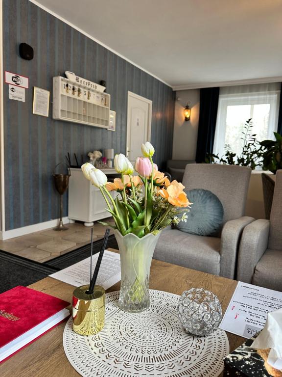 eine Vase mit Blumen auf einem Tisch im Wohnzimmer in der Unterkunft Jager Guesthouse in Sopron