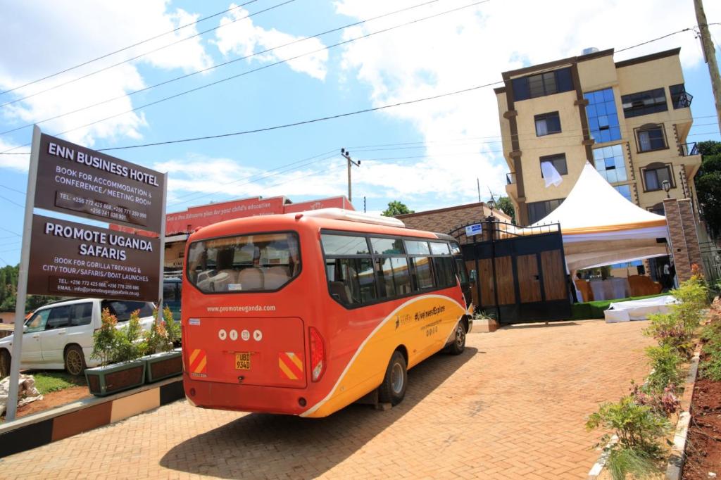a red and yellow bus parked next to a sign at Enn Business Hotel in Kampala