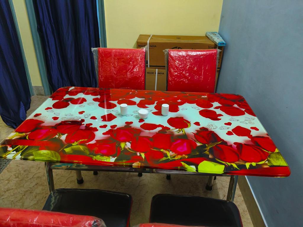 una mesa con flores rojas en ella con dos sillas en Behala home stay, en Calcuta