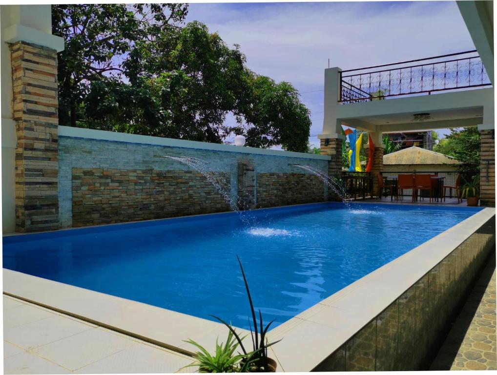 uma grande piscina azul em frente a uma casa em Bountiful Inn em Puerto Princesa