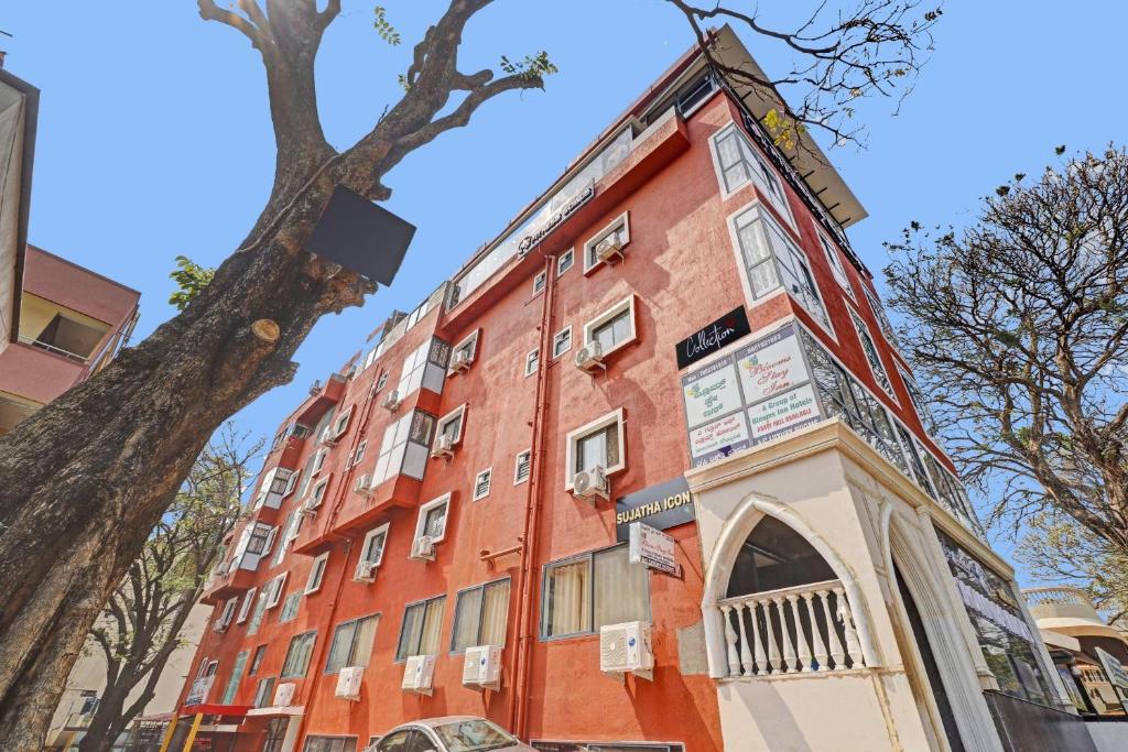 un edificio rojo con un árbol delante de él en Super Capital O Blooms Stay Inn Near Snow City en Bangalore