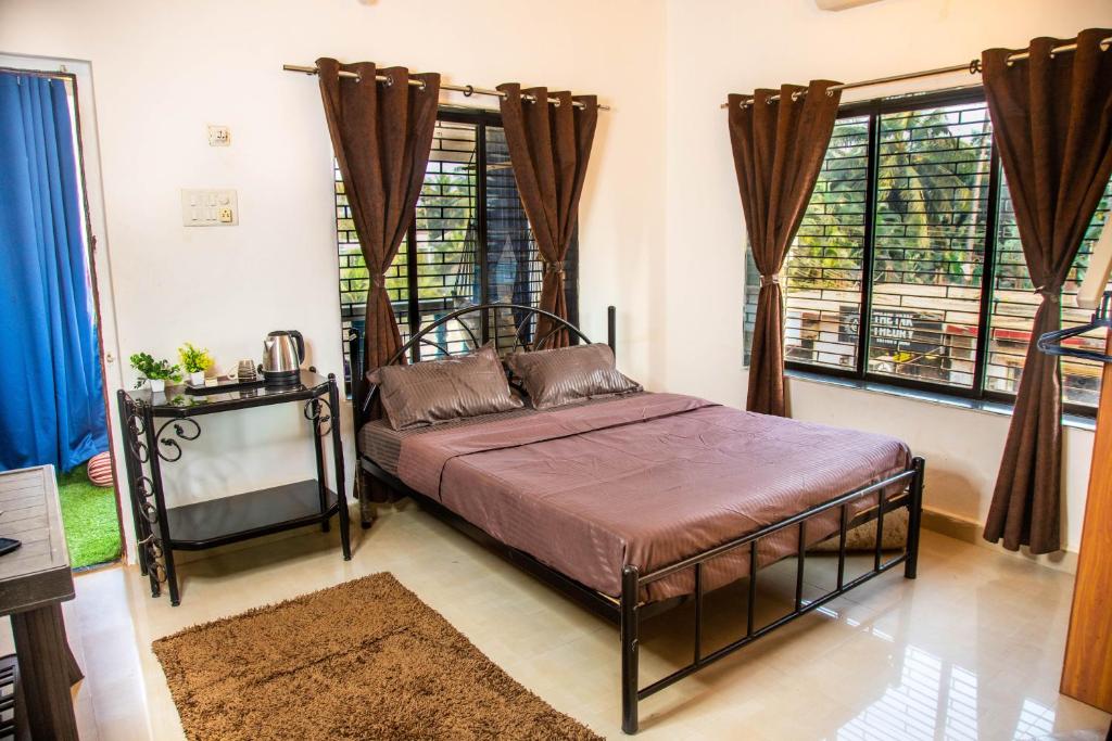 1 dormitorio con 1 cama en una habitación con ventanas en Beyond the Reef - NestinGoa Homestays en Arambol