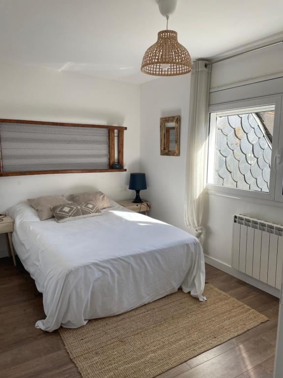 Un dormitorio con una gran cama blanca y una ventana en Ático con encanto en Cerdanya, en Martinet