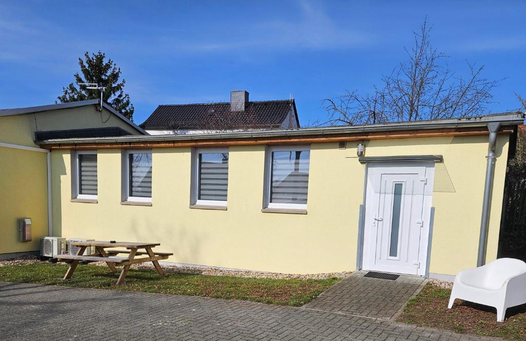 a yellow house with a picnic table and a bench at Gästewohnung Vesta in Bad Dürrenberg