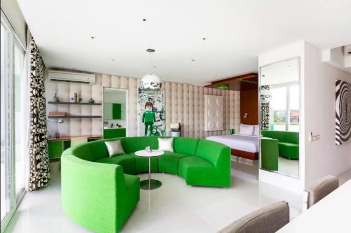 a living room with a green couch and a bed at Chill Hotel Seminyak in Seminyak