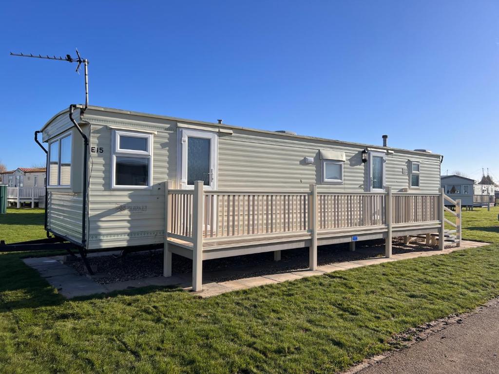 a mobile home with a porch and a fence at AMS Caravan Holidays in Ingoldmells