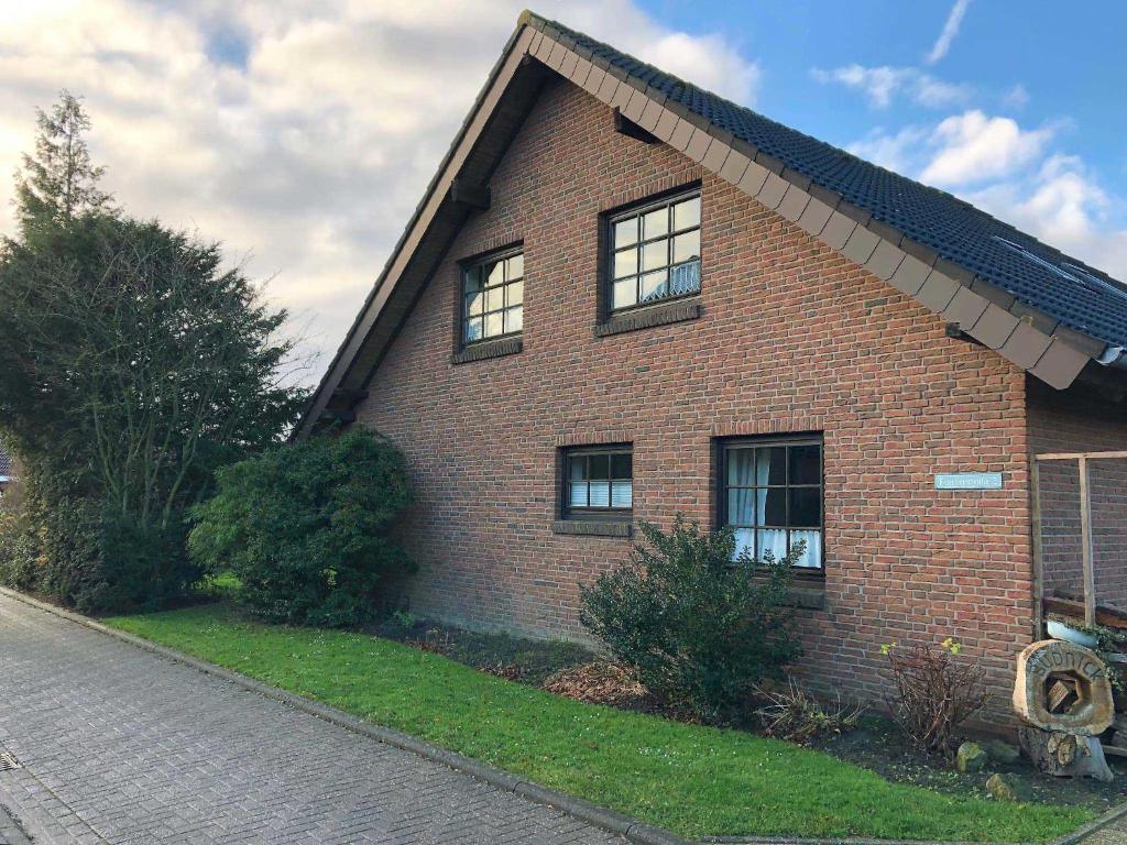 a red brick house with windows on a street at Haus Margret in Carolinensiel