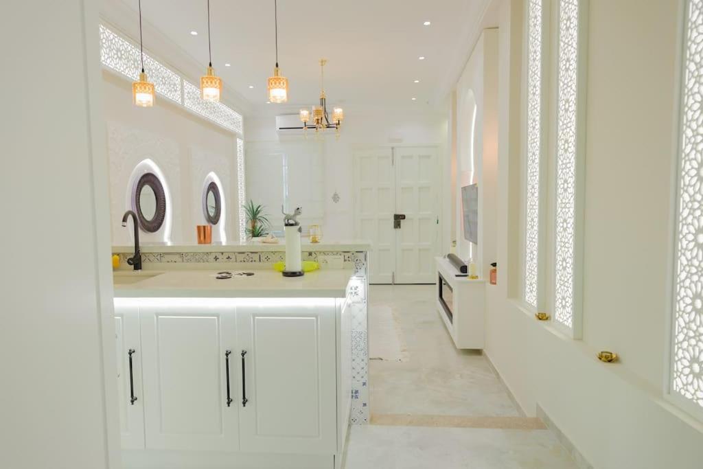 W białej łazience znajduje się umywalka i lustro. w obiekcie Maison SOUAD w mieście Mahdia