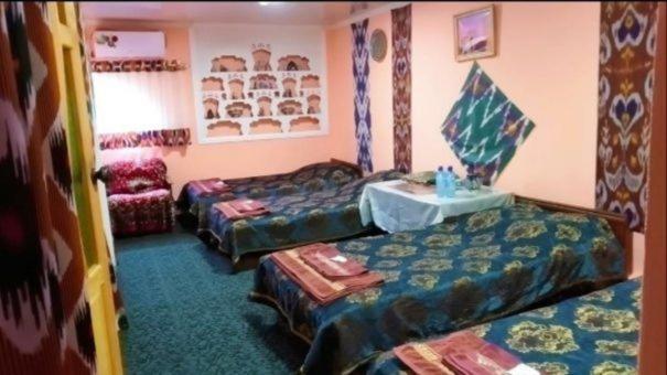 a room with two beds and a table in it at Fayz Hotel in Bukhara