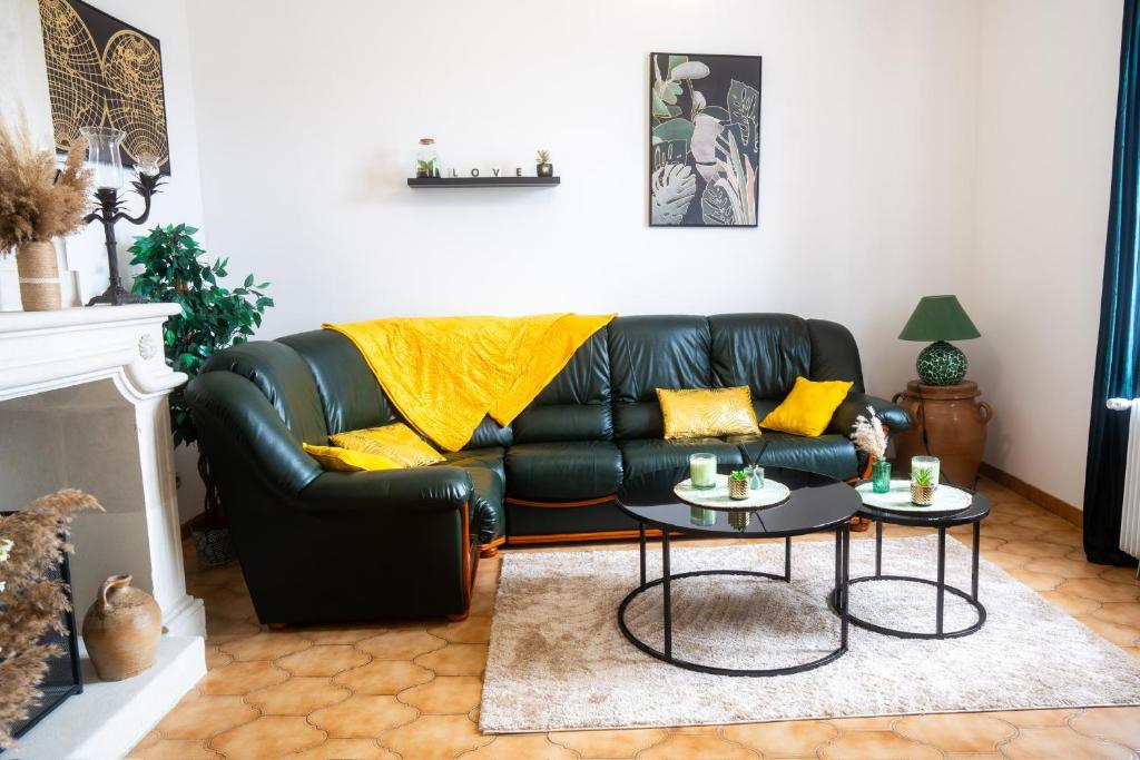 a black leather couch with yellow pillows in a living room at 100 m2 entre Angers et saumur proche châteaux in Saint-Clément-des-Levées