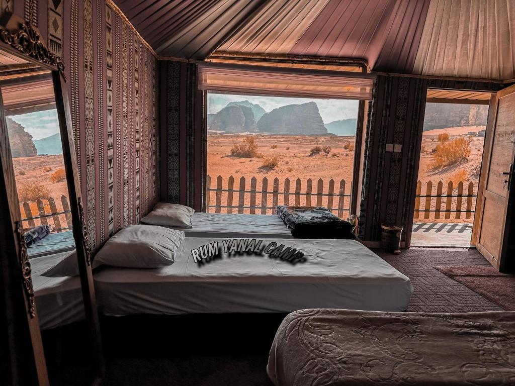 two beds in a room with a view of the desert at RUM YANAL CAMP in Wadi Rum