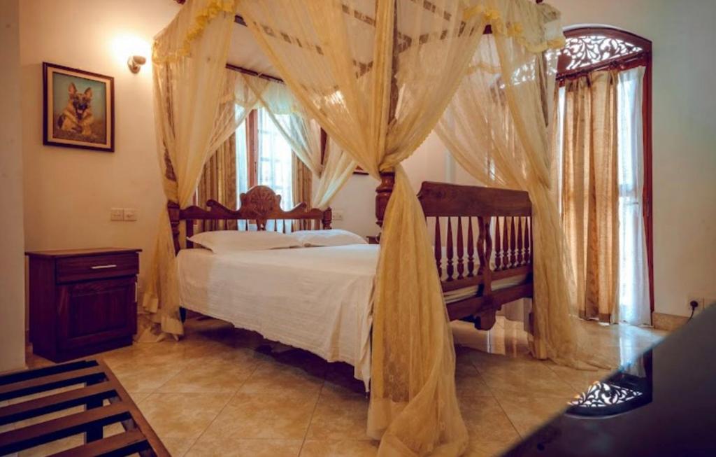 1 dormitorio con cama con dosel y cortinas en Village Inn Resort, en Negombo