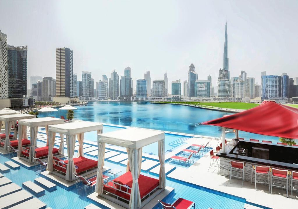 a pool with chairs and tables and a city skyline at Canal Central Hotel in Dubai