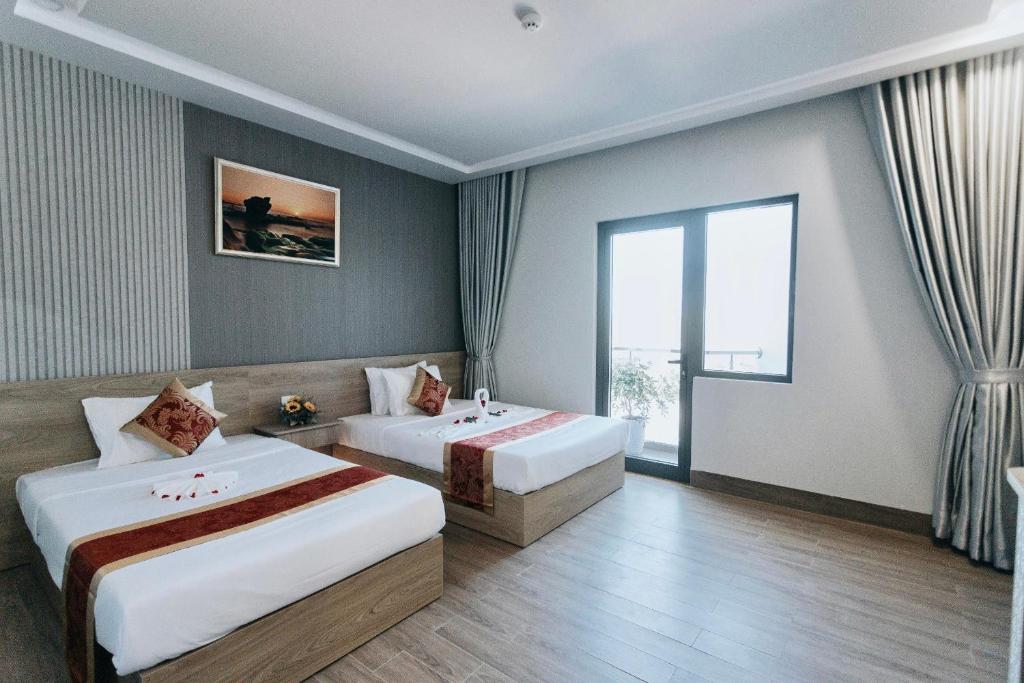 ein Hotelzimmer mit 2 Betten und einer Badewanne in der Unterkunft Khoa Hotel Phan Thiết in Ấp Bình Hưng