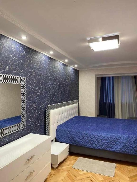 1 dormitorio con cama y pared azul en Dighomi Apartment, en Tiflis