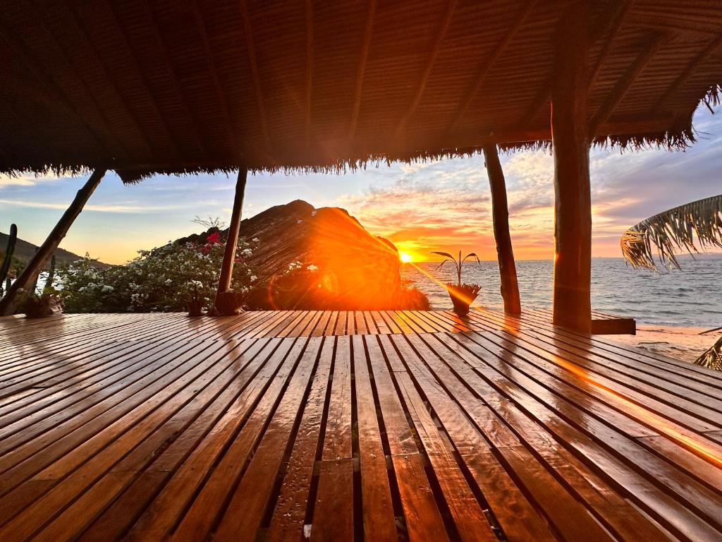 a wooden deck with the sunset in the background at Shambala Madagascar: Beachfront Lodge And Adventures in Ambolobozo