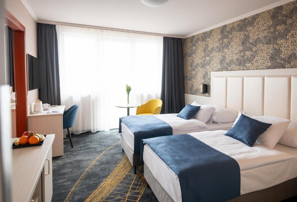 a hotel room with two beds and a table at Airport Hotel Budapest in Vecsés