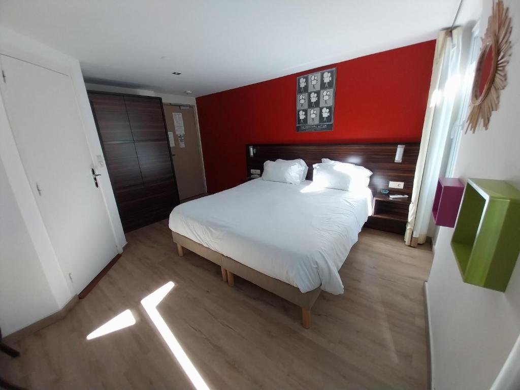 a bedroom with a white bed with a red wall at Hotel Le Mistral in Cannes